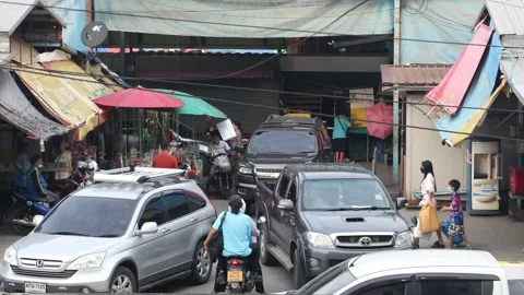 Heavy traffic at a small intersection next to the market at dusk Stock Footage 219487506