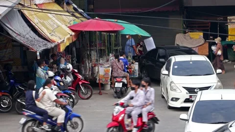 Heavy traffic at a small intersection next to the market at dusk Stock Footage 223369579