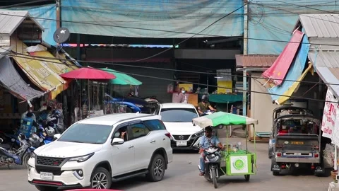 Heavy traffic at a small intersection next to the market at dusk Stock Footage 240001942