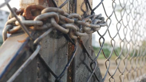 Heavy weathered metal chain wrapped around rusty steel fence Video stock 329145292