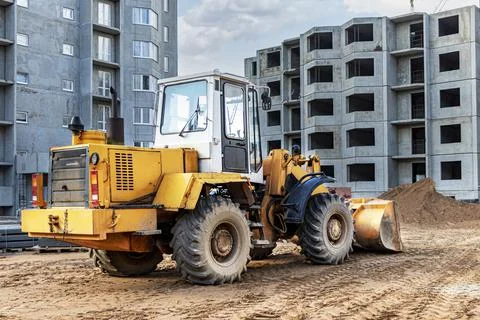 Heavy wheel loader with a bucket at a construction site. Photos