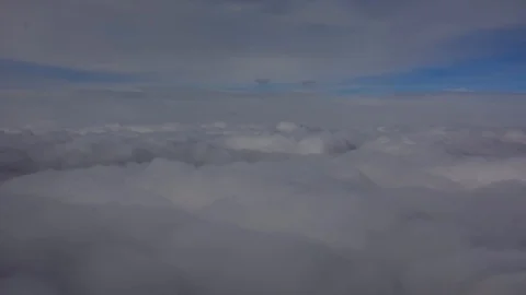 Heavy white / grey clouds from the view on a airplane, with blue sky and suns Stock Footage 105876809