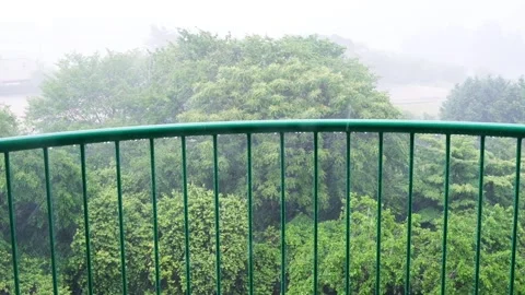 Heavy wind and rain seen from the terrace, trees are shaking due to the win.. Stock Footage 325643598