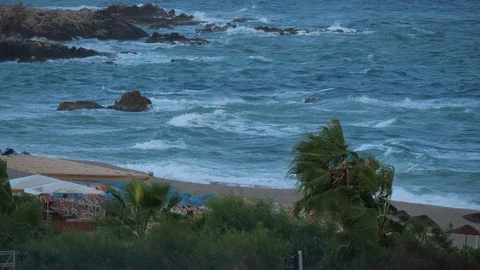 Heavy wind on a sandy resort beach and storm at sea or ocean. Video stock 119336990