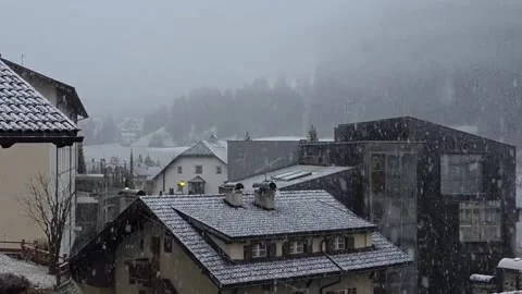 Heavy winter snow falling over roofs of modern mountain town houses Stockbeeldmateriaal 348642891