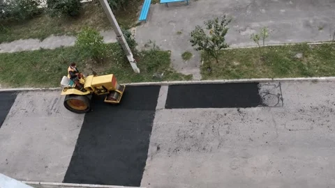 Heavy yellow steamroller compacting a newly paved rectangular asphalt patch.. Stock Footage 339802228