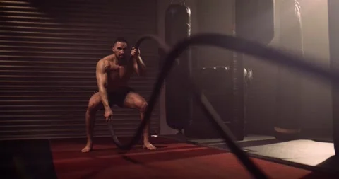 A Heavyweight Hispanic Weightlifter Exercises Battle Ropes In An MMA Gym Stock Footage 158407904