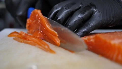 Hef using fish fillet knife cutting fresh orange salmon meat on cutting board in Stock Footage 283003169