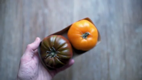 Heirloom tomato, two tomatoes vegetable in bag container hand holding Stock Footage 330297045