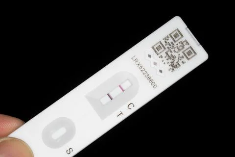 Held by finger tips, a lateral flow test strip close-up, a positive test result. Foto stock