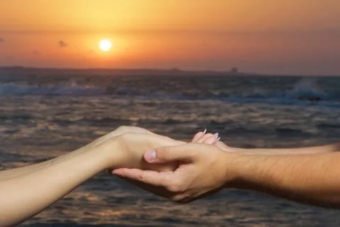 Held hands in the background of the sun and the sky. Hands of holding each ot Stock Photos