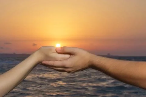Held hands in the background of the sun and the sky. Hands of holding each ot Stock Photos