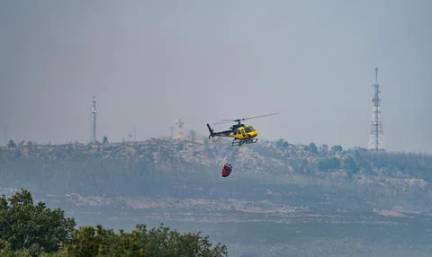 Helicopter in Action Fighting Forest Fire with Water Stock Photos
