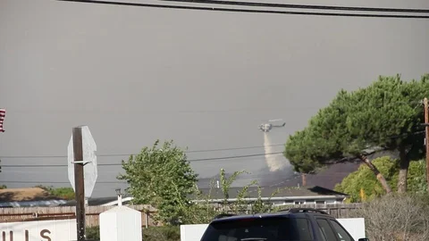 Helicopter in the background drops water over fire Stock Footage 114414910