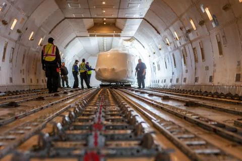 Helicopter being loaded inside large cargo airplane Stock Photos