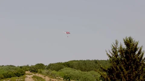 A helicopter carrying water to drop on a forest fire. Rocca di Mezzo. Abruzzo Stock Footage 341072496