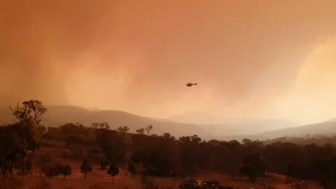 A Helicopter Circles Around Orange Sky, Toward Bushfire Stock Footage 195281237