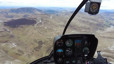 Helicopter cockpit view inside front windmills wind turbines turning below Stock Footage 265453251
