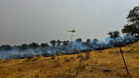 A helicopter in the distance is working on a fire. Stock Photos