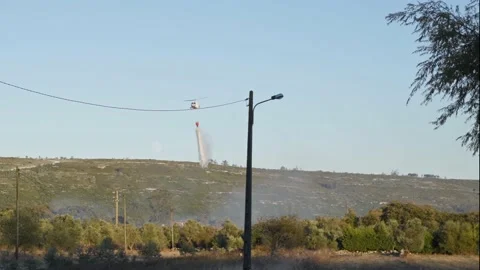 Helicopter dropping water on fire in firefighting mission, slow motion Stock Footage 139147410