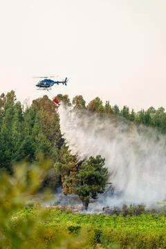 Helicopter fighting forest fire dropping water in spain Stock Photos