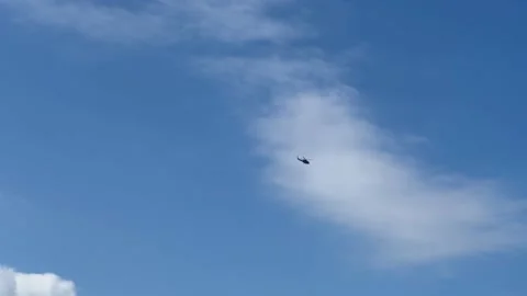 A helicopter flies in the background of a white cloud and blue sky. Stock Footage 239654086