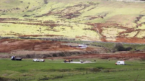 Helicopter flies with building materials in underslung hopper Peak District Stock Footage 80133826