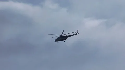 Helicopter flies in cloudy sky and disappears behind the hill Video stock 78306456
