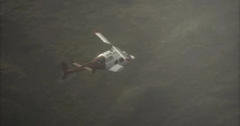 Helicopter flies low over rugged terrain during misty afternoon Illustrazione stock