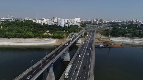A helicopter flies over the bridge over the river, on which there go cars Stock Footage 128997370
