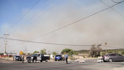 Helicopter flies over cops and road block towards fire Stock Footage 114413414