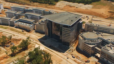 Helicopter flies over new large buildings and a nearby motorway Stock Footage 92201985