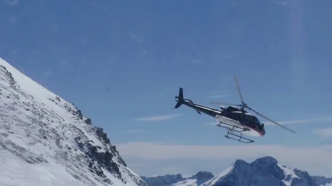 Helicopter flies over the snow covered peaks of a mountain Stock Footage