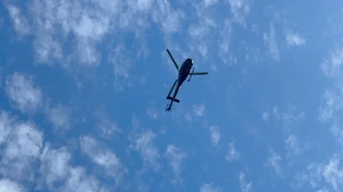 Helicopter flies overhead with blue cloudy sky Stock Footage 314236622