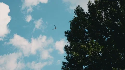 A helicopter flies in the sky over the forest. Shooting from the ground Видео 143298053