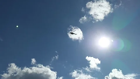 Helicopter flies through the sky through the clouds and the sun Stock Footage 247185540