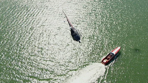 Helicopter flies under camera and over speed boat on the water Stock Footage 136200458
