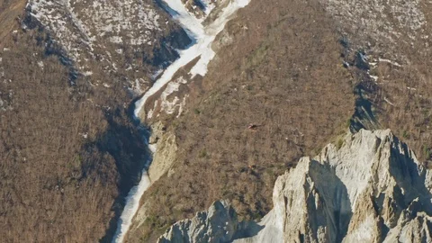 Helicopter fly above sharp rocky cliffs in mountains, giant severe snowy slopes Stock Footage 127081477