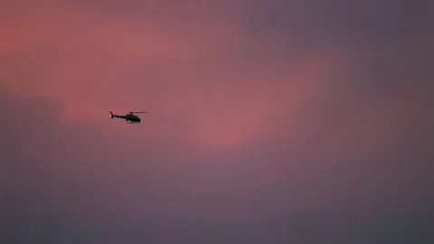 Helicopter flying across clouds. Sunset Vidéo 76259390