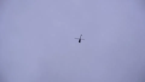 Helicopter Flying in Gray Cloudy Sky Tracking Shot Stock Footage 323398810