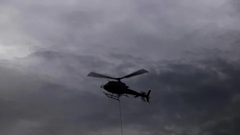 Helicopter Flying with a Hanging Cable in Beautiful Storm Cloudscape in Видео 293256517