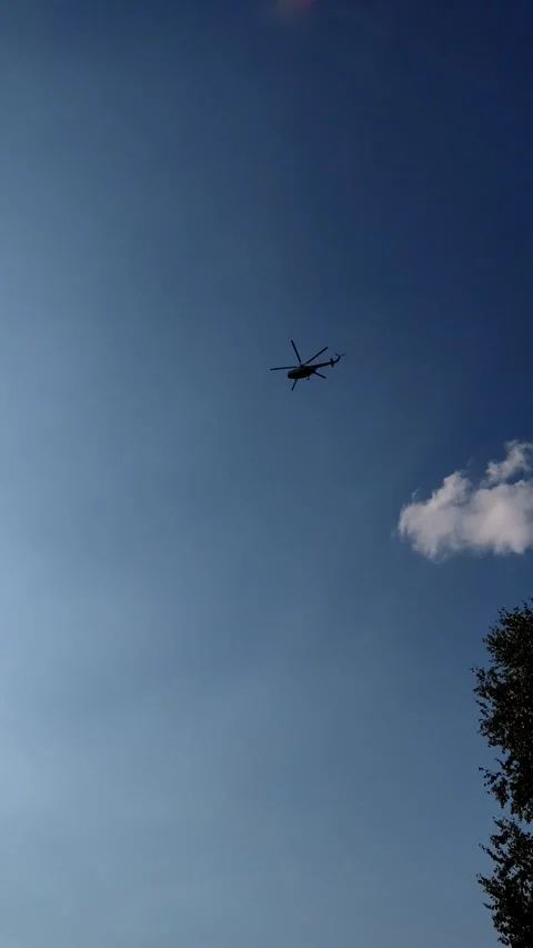 Helicopter flying high in the blue sky above a red roof. Stock Footage 341134565