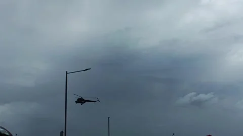 Helicopter flying low across dramatic overcast sky with dark clouds and street Stock Footage 341657754