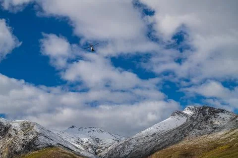 Helicopter flying over snow capped mountains Stock Photos