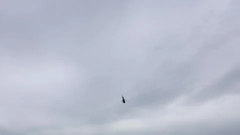 Helicopter flying solo across dramatic overcast sky with dynamic tilt capturing  Stock Footage 311150293