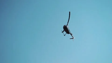 Helicopter flying through clear blue sky, performing aerial maneuvers with Stock Footage 328481021