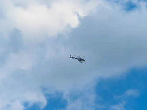 Helicopter flying through a partly cloudy blue sky Stock Photos
