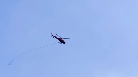 Helicopter with a Hook Flying Against Blue Sky with Clouds and a Tree Mountain Video stock 241808730