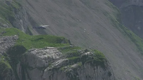 Helicopter hovering near side of mountain Stockbeeldmateriaal 12677085