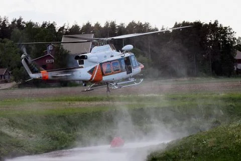 Helicopter hovering over a small river to fill a bucket with water Stock Photos